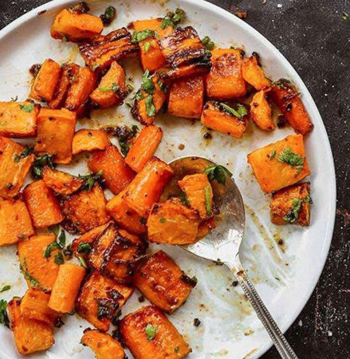 Roasted spiced carrots with herbs on a white plate